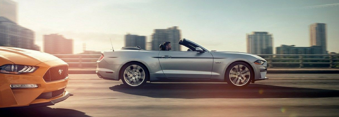 Silver 2019 Ford Mustang convertible driving down the highway at sunset