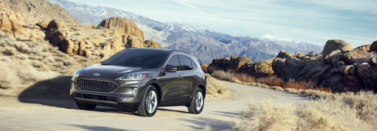 2020 Ford Escape in gray driving along a dirt road in mountainous terrain.